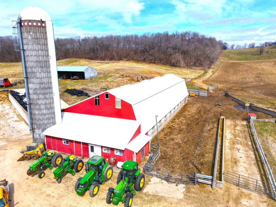 N41286 Halama Road, Independence WI 54747 - Red gambrel barn with attached silo and multiple John Deere tractors parked in yard - MLS #1599441 - image6