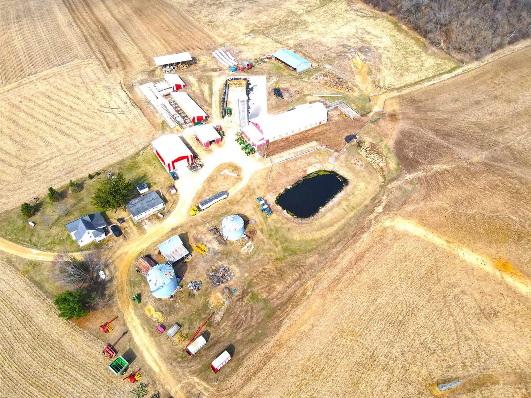 N41286 Halama Road, Independence WI 54747 - Aerial of farmstead with grain bins, round pond, red barns, and farmhouse visible from above - MLS #1599405 - image10