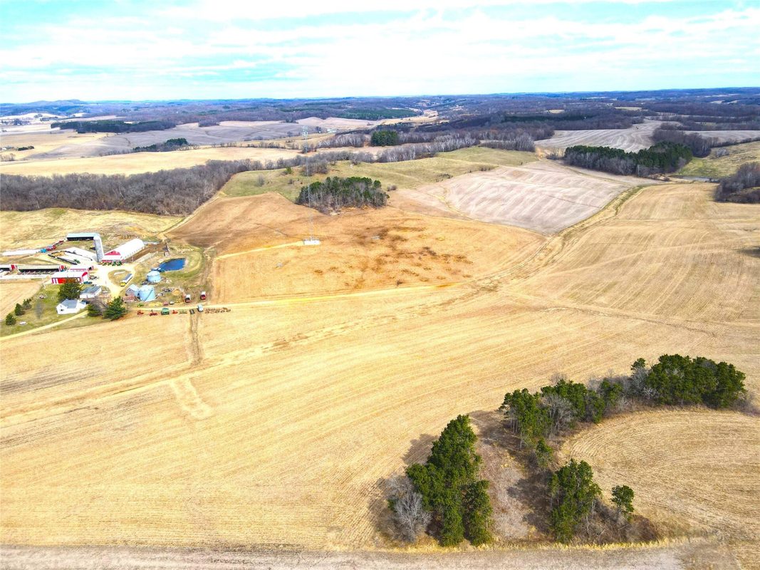 N41286 Halama Road, Independence WI 54747 - Wide aerial showing farmstead at left and expansive harvested fields with wooded knoll at right - MLS #1599405 - image8