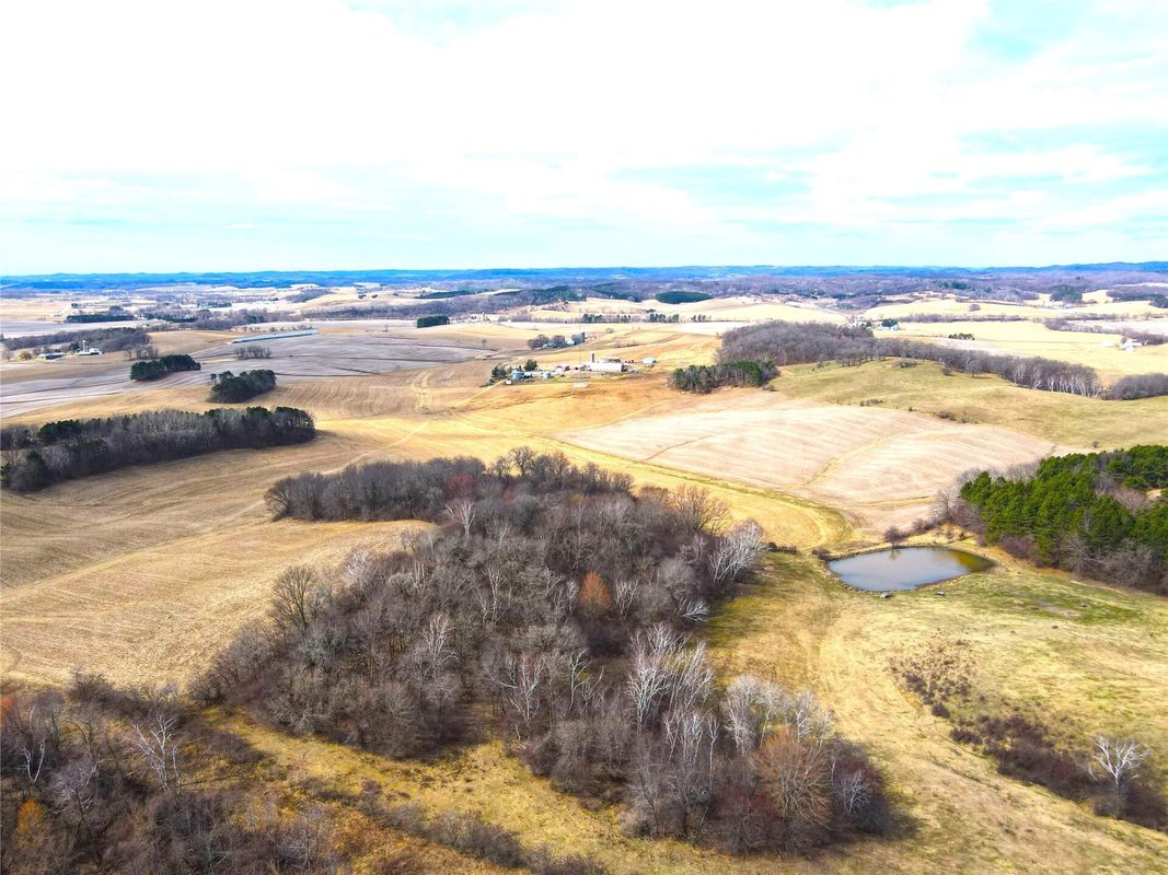 N41286 Halama Road, Independence WI 54747 - Aerial of wooded draw with small pond at edge of harvested crop field, far-ranging view - MLS #1599405 - image16